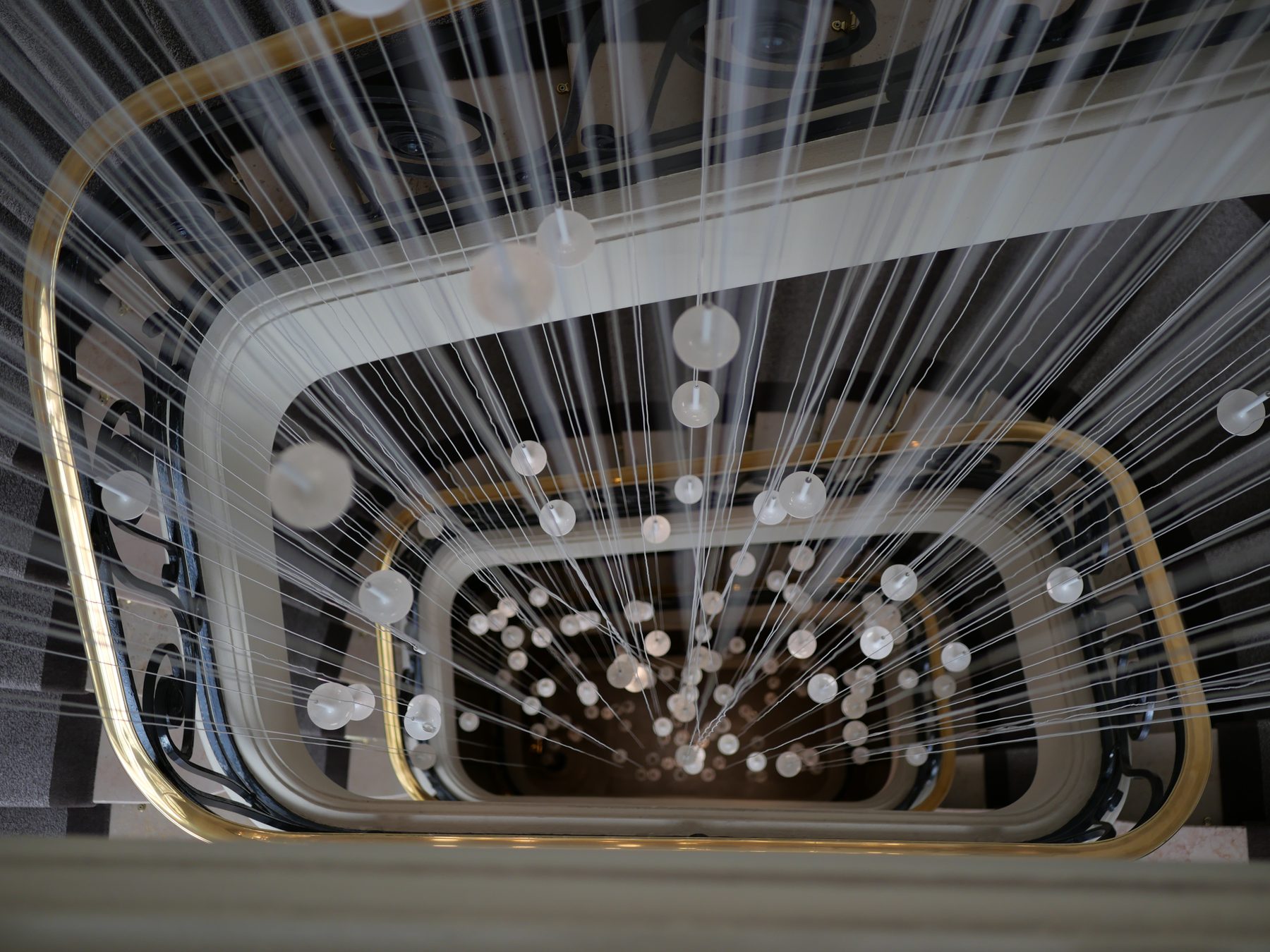Cage d’escalier vue en contre-plongée et suspension lumineuse